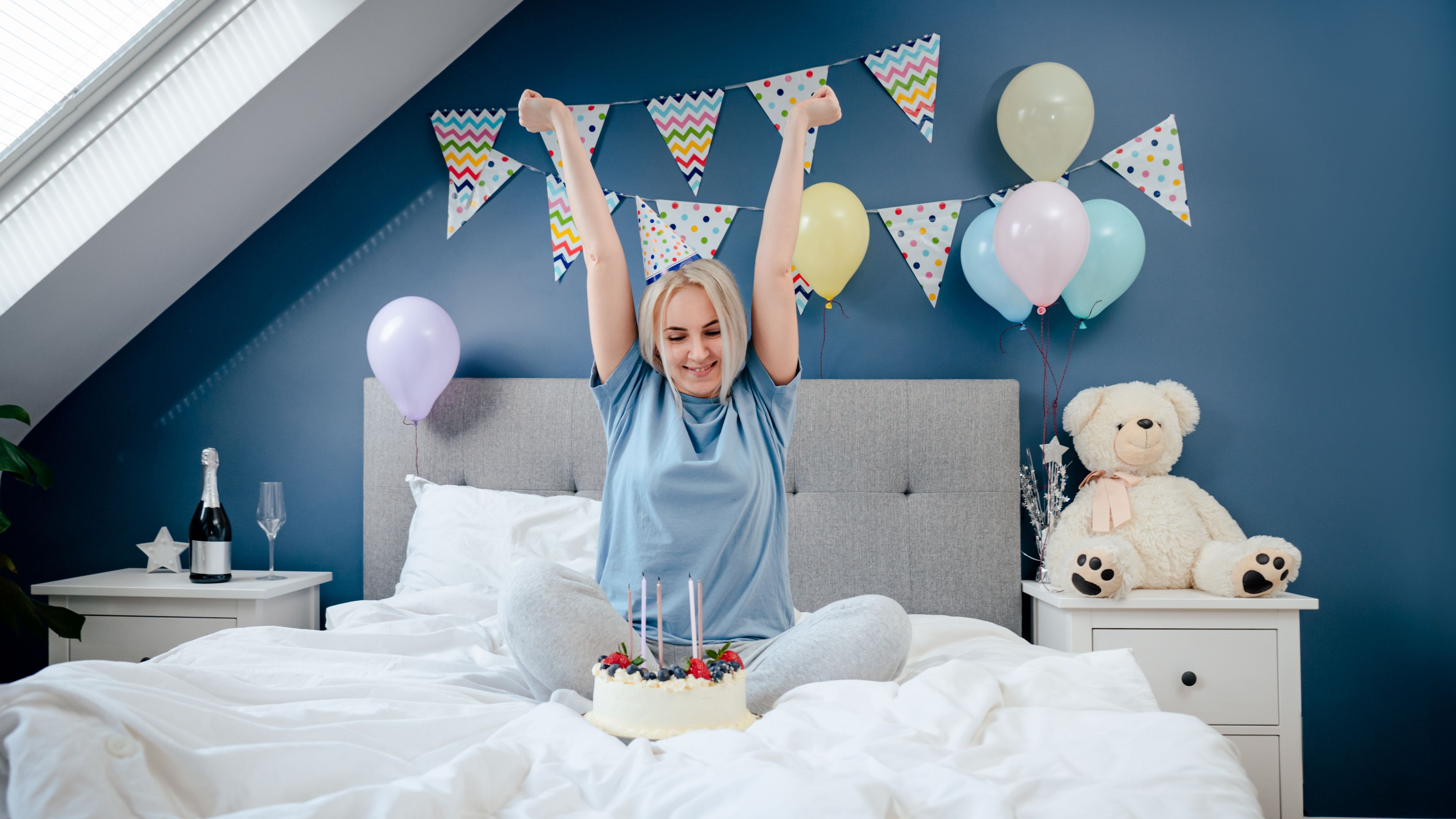 A cheerful woman sits next to a birthday cake