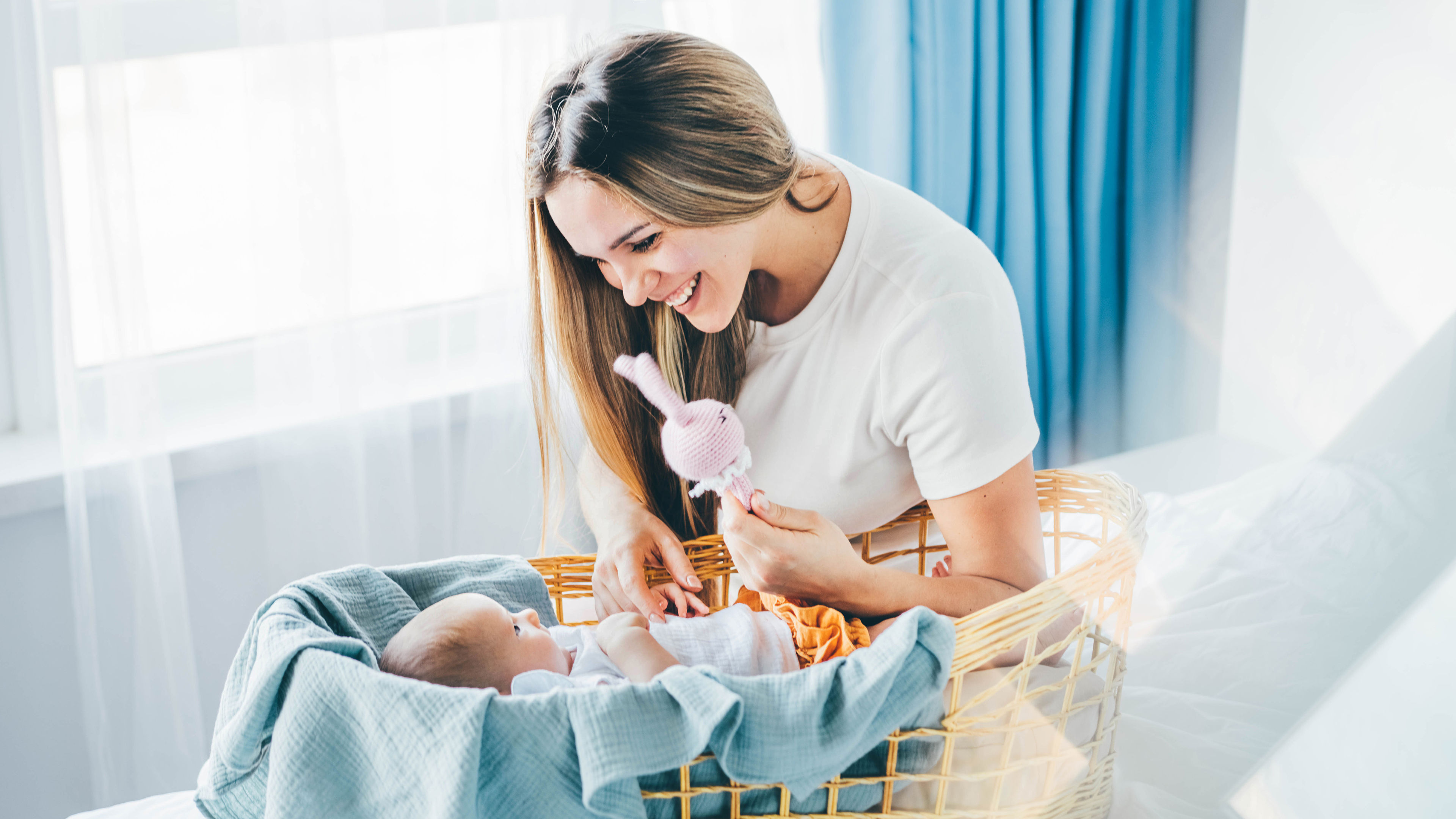 A happy mother smiles at her baby lying in a bassinet