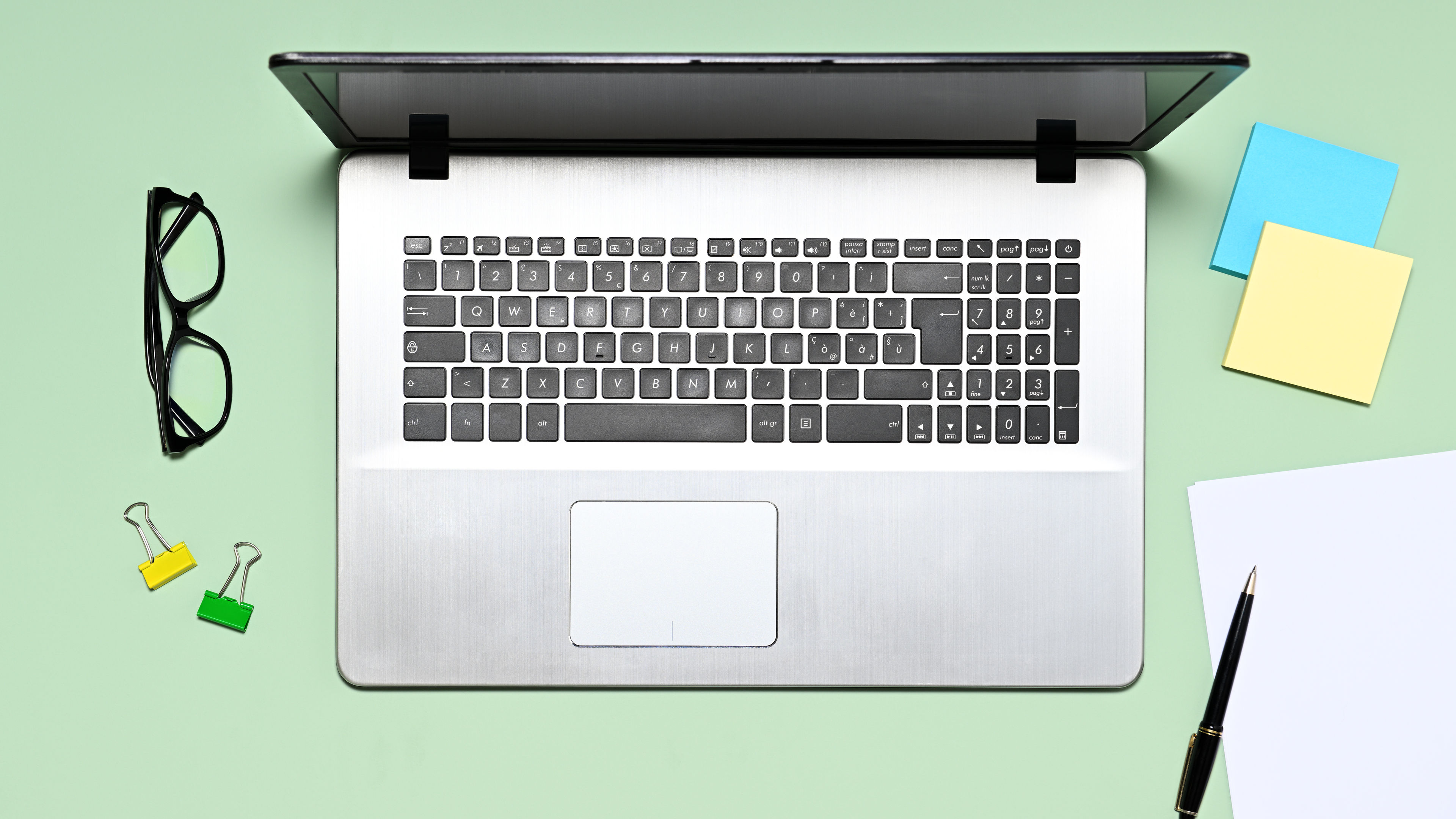 A laptop sits on a mint-green desk.