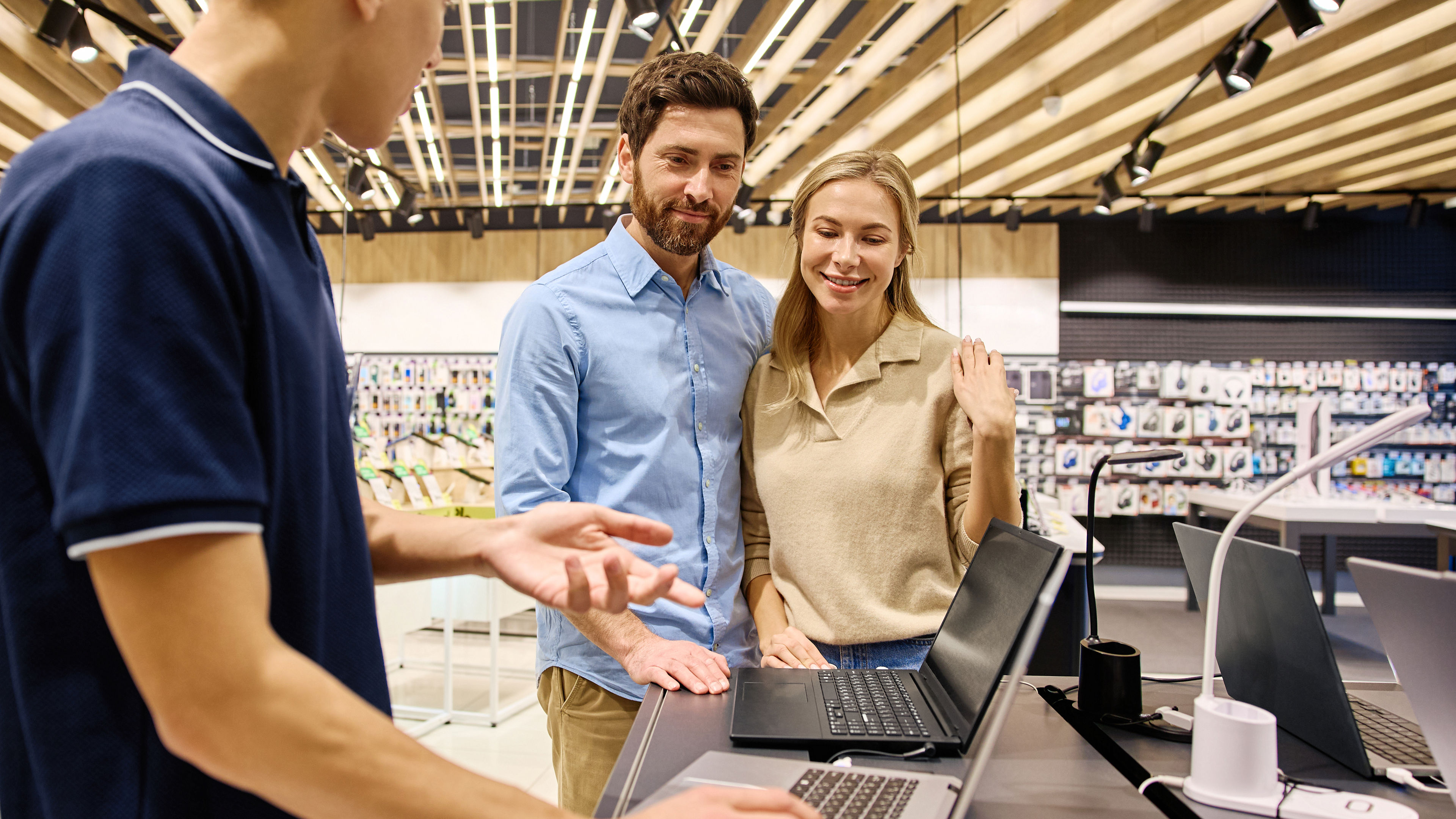 A man and woman looking at two laptops.
