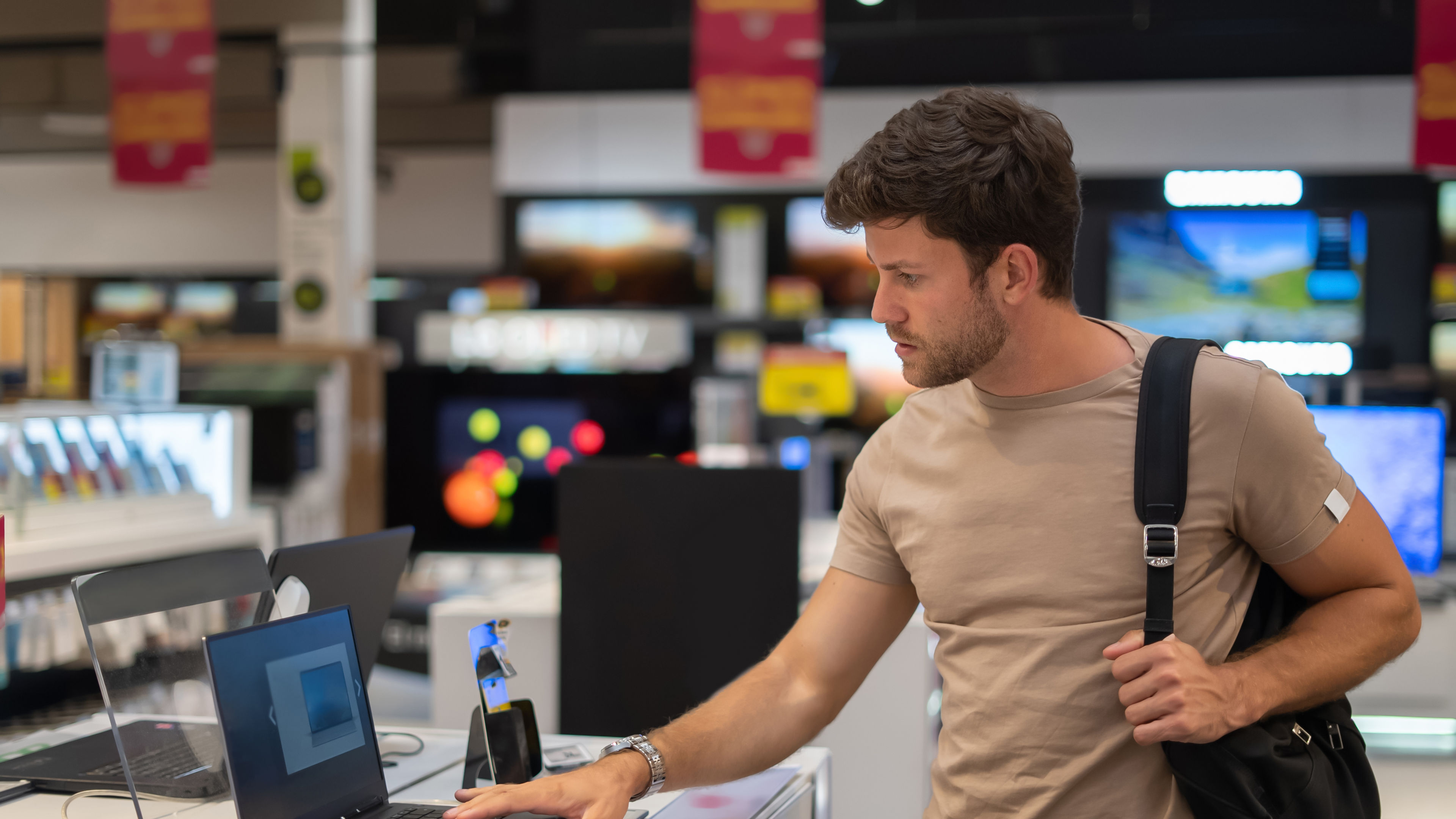 A man looking at a laptop in a shop. 