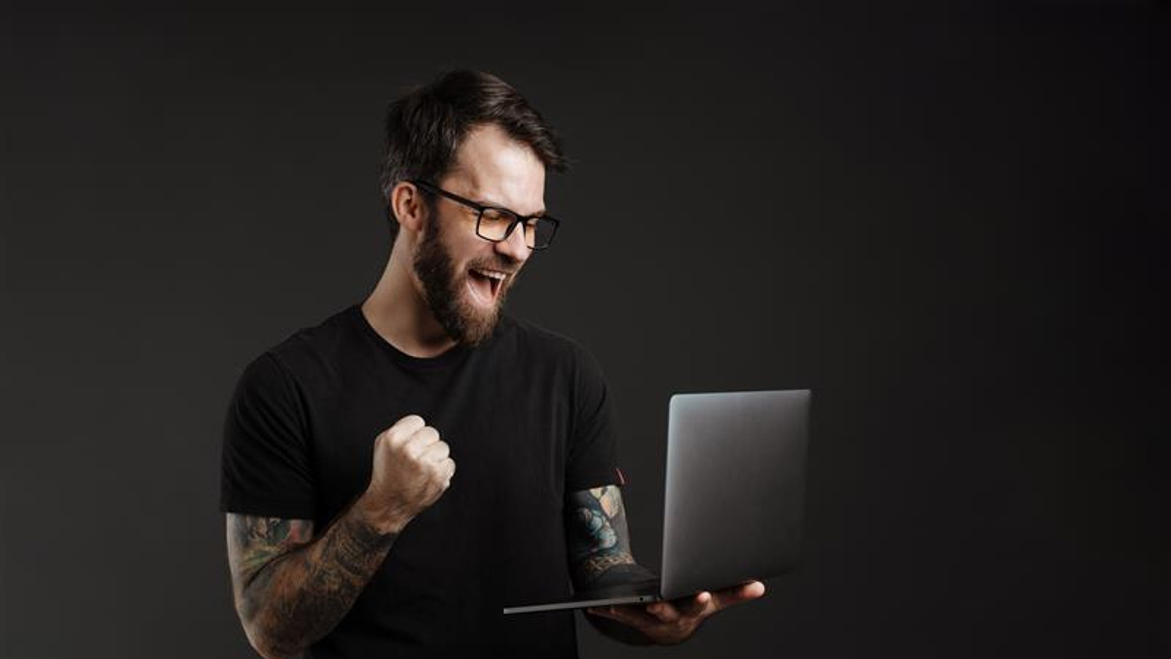 A man making a winner's gesture and using a laptop. 