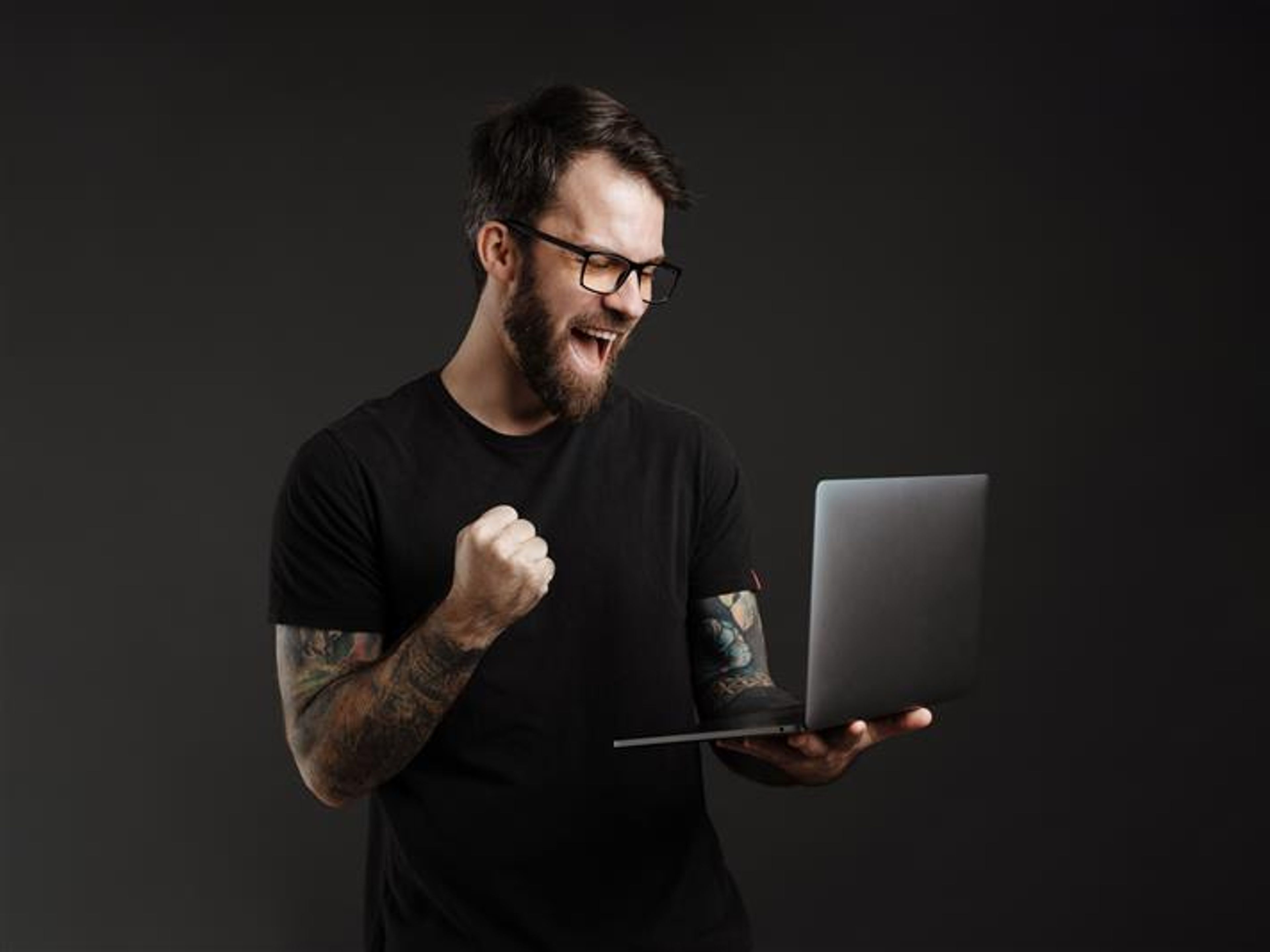 A man making a winner's gesture and using a laptop. 