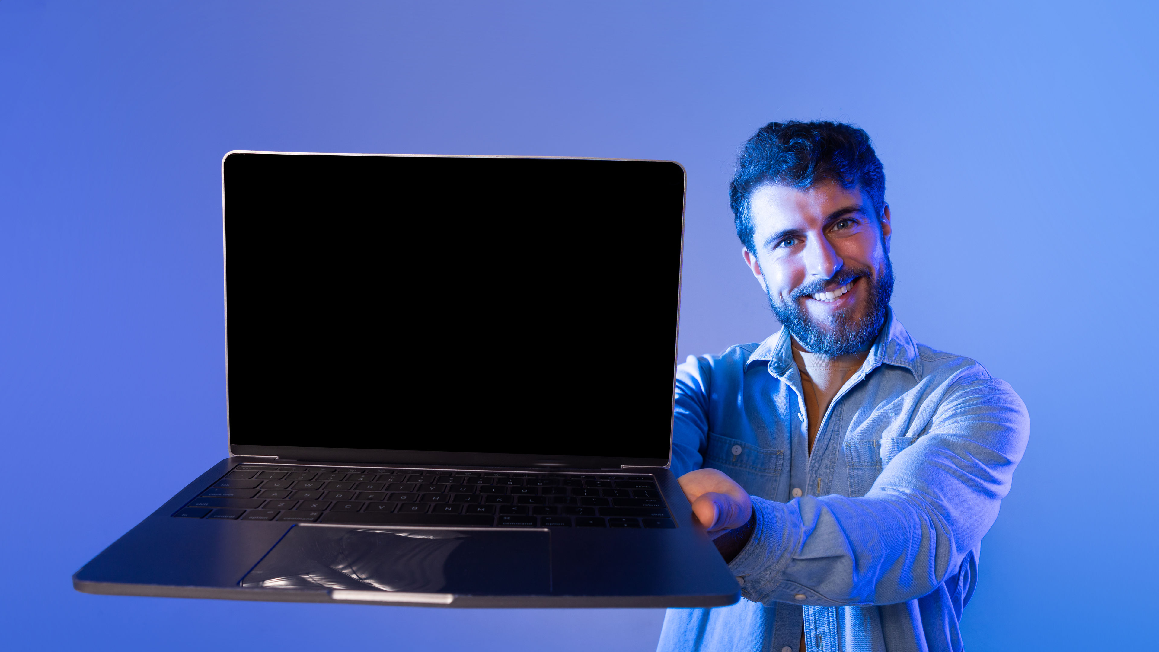 A smiling man is holding a laptop.
