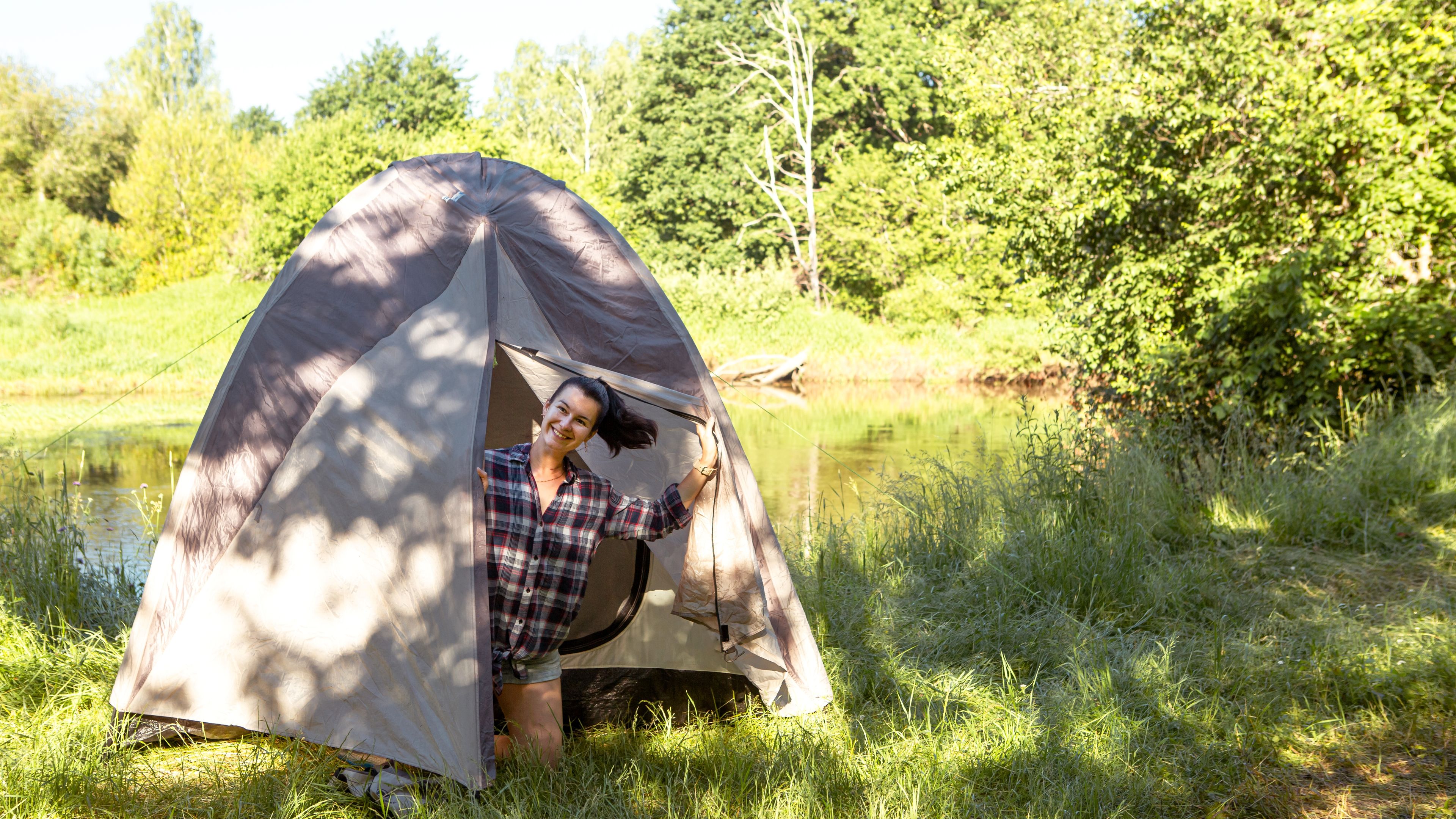 A smiling woman peeks out from a tent.