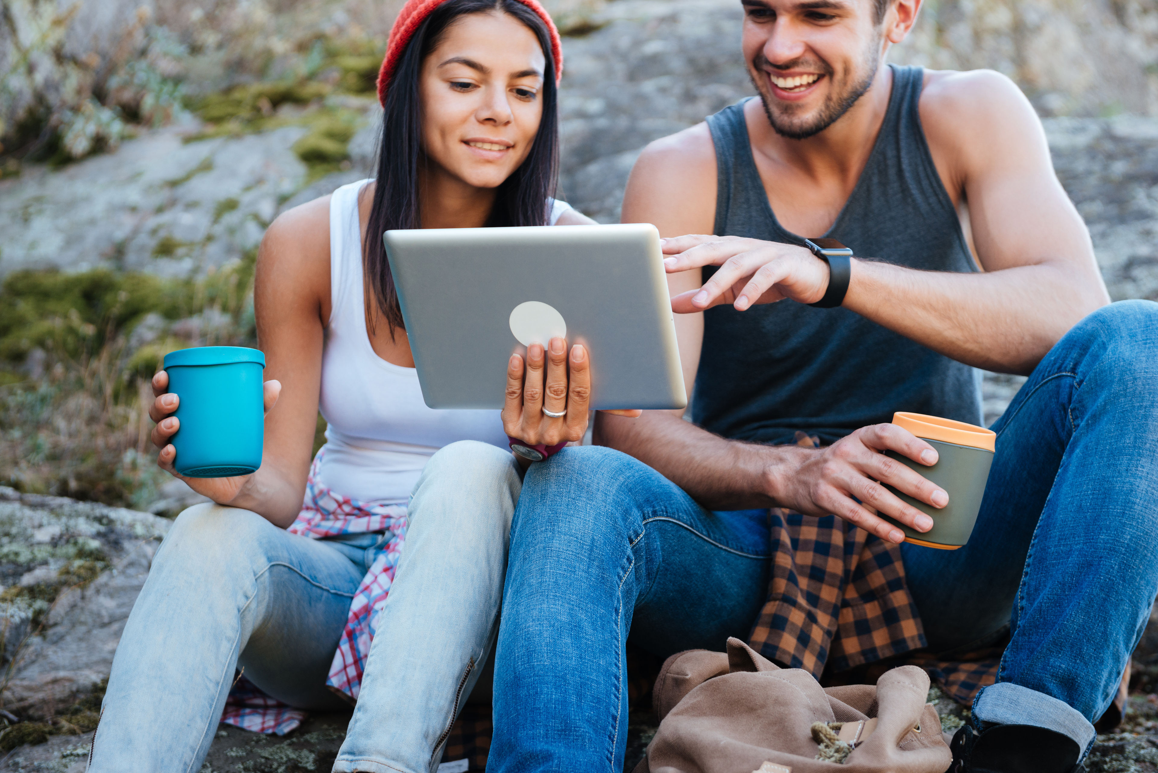 A smiling young couple using a tablet computer on a camping trip