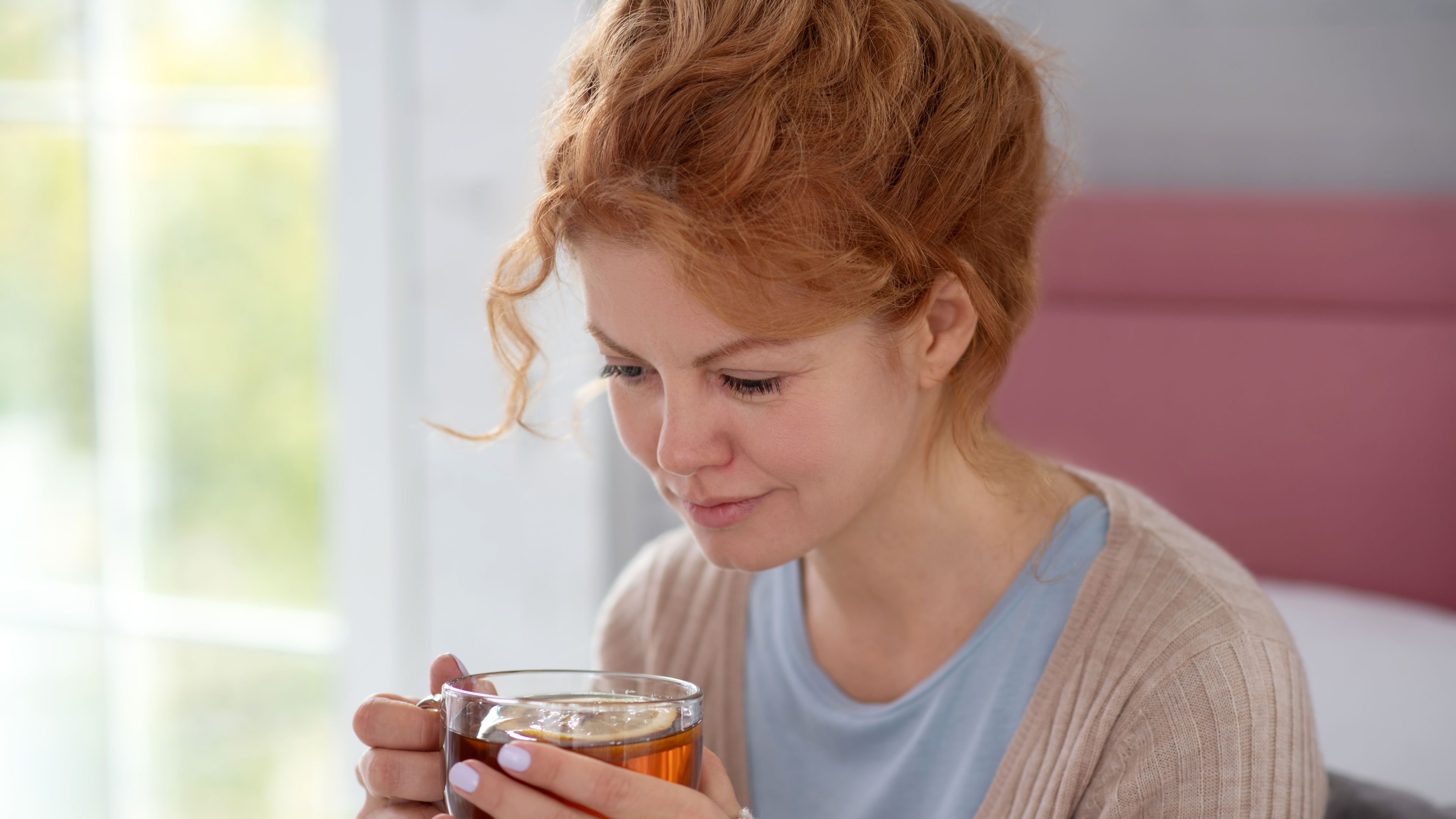 A woman holding a cup of tea with lemon.