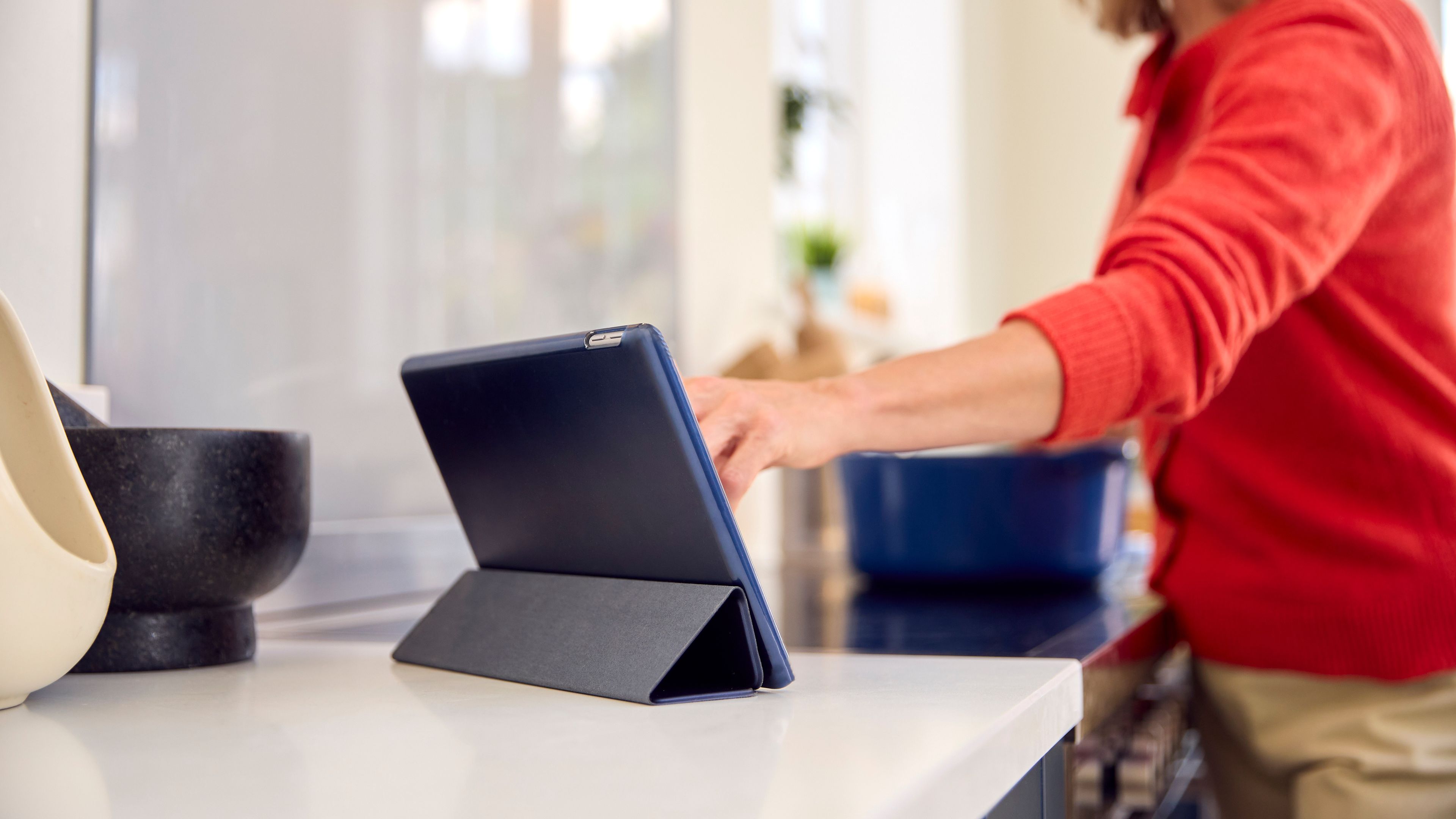 A woman in orange dress touching the iPad