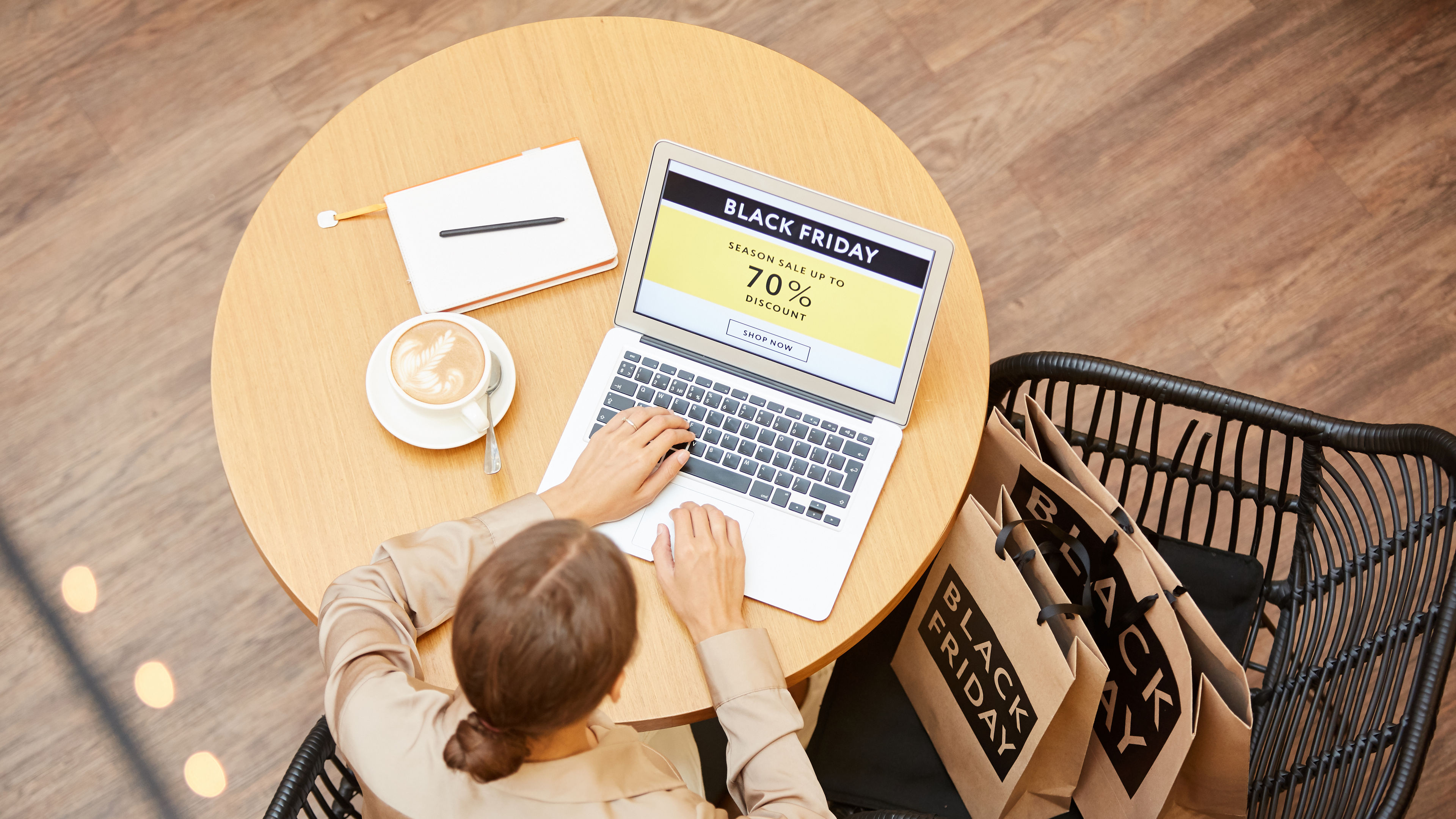 A woman sitting in a café, browsing online deals on her laptop 