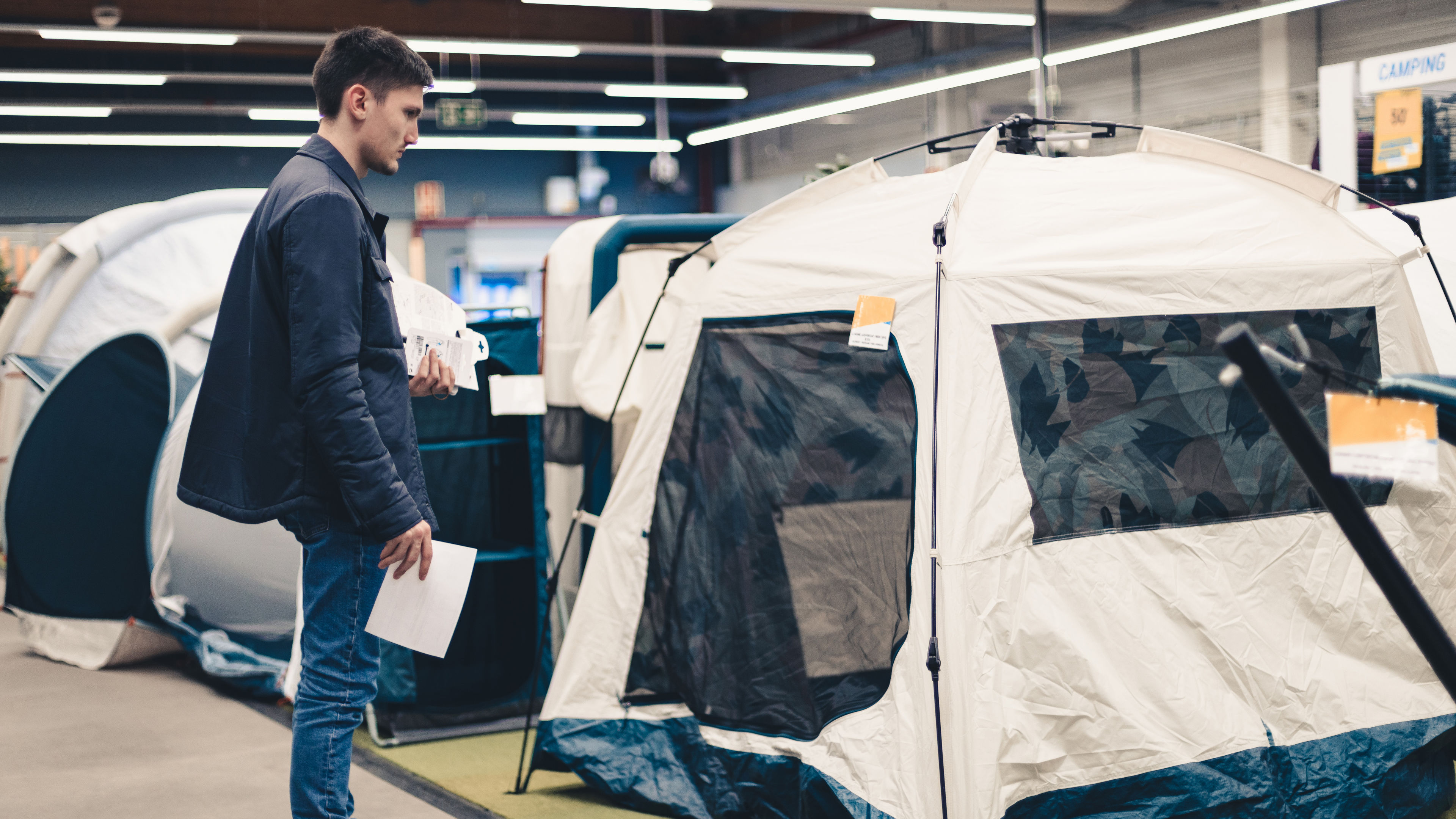 A young man carefully looking at a tent. 