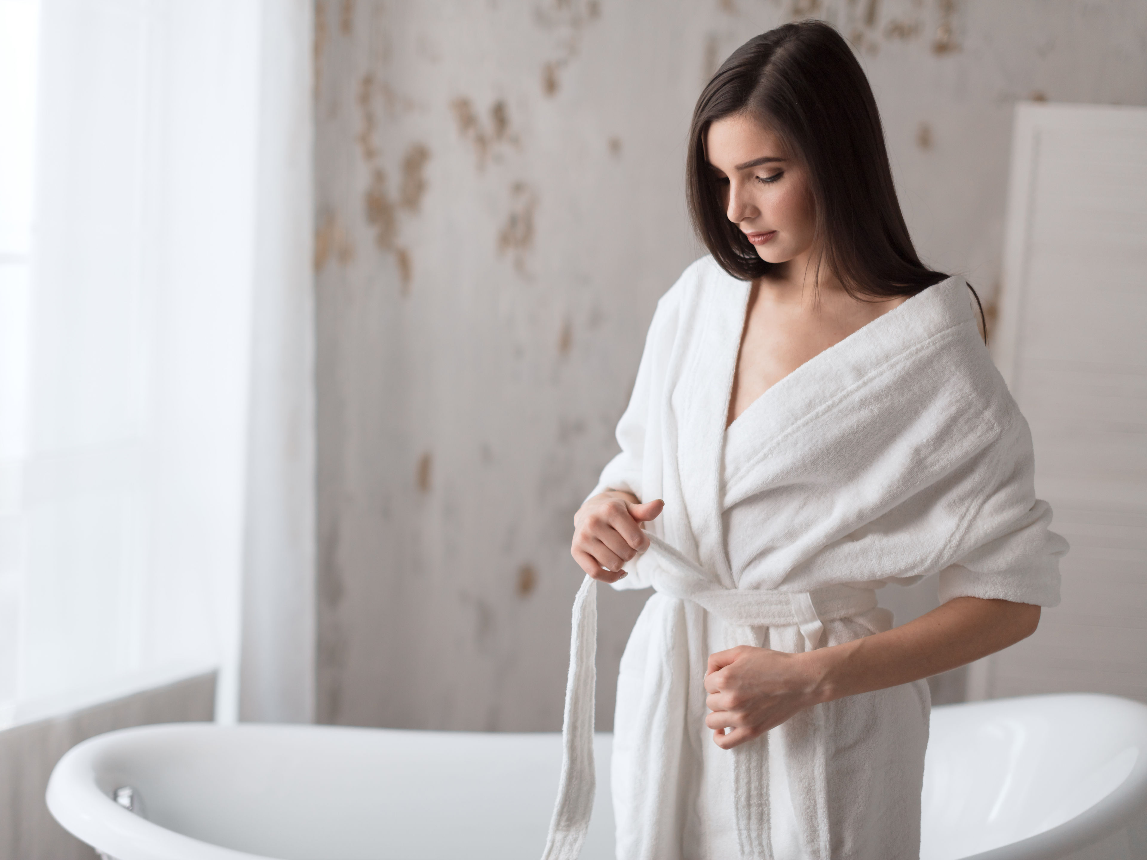 A young woman is wearing a white bathrobe