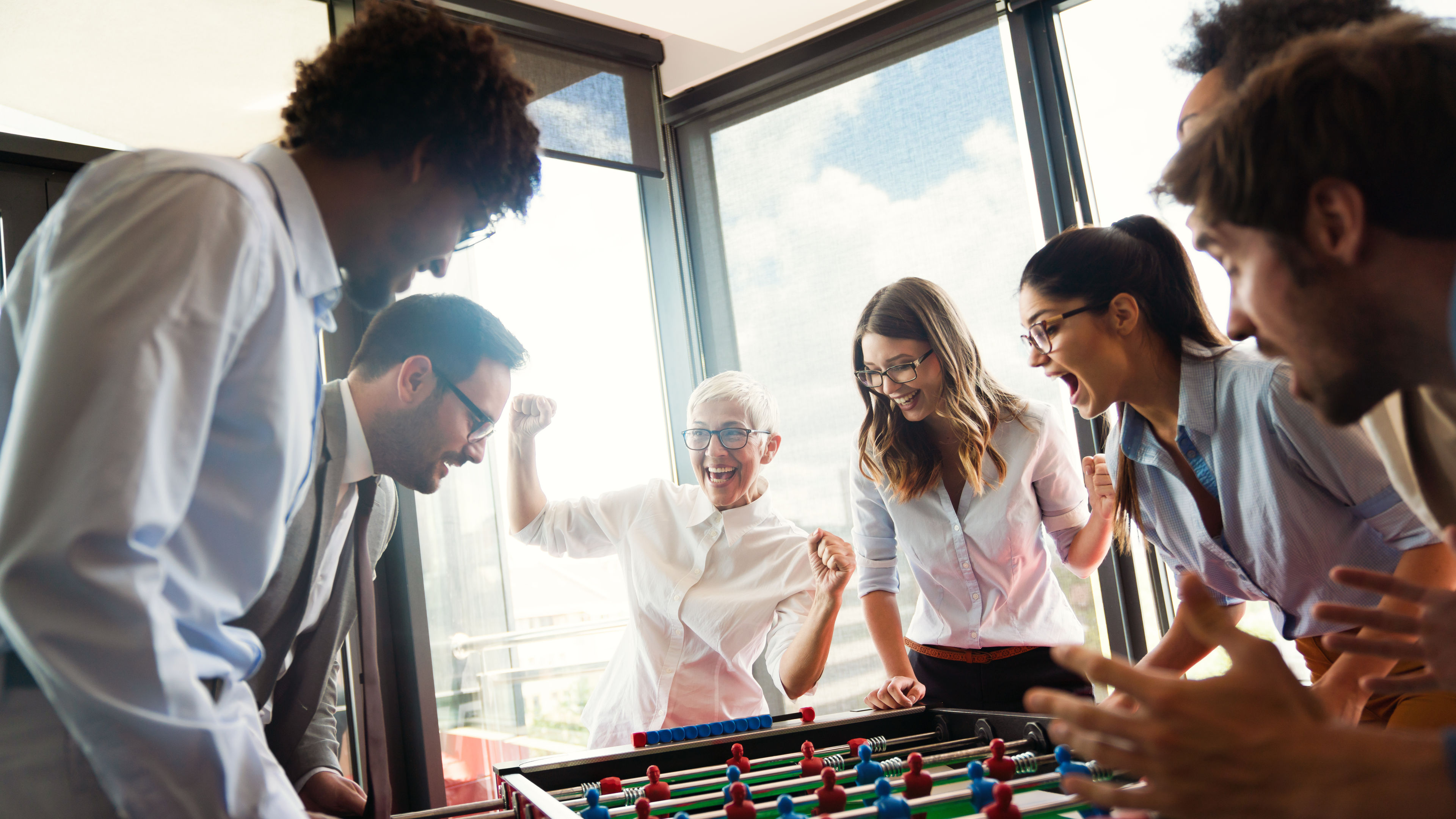 Business people having great time together.Colleagues playing table football in modern office 