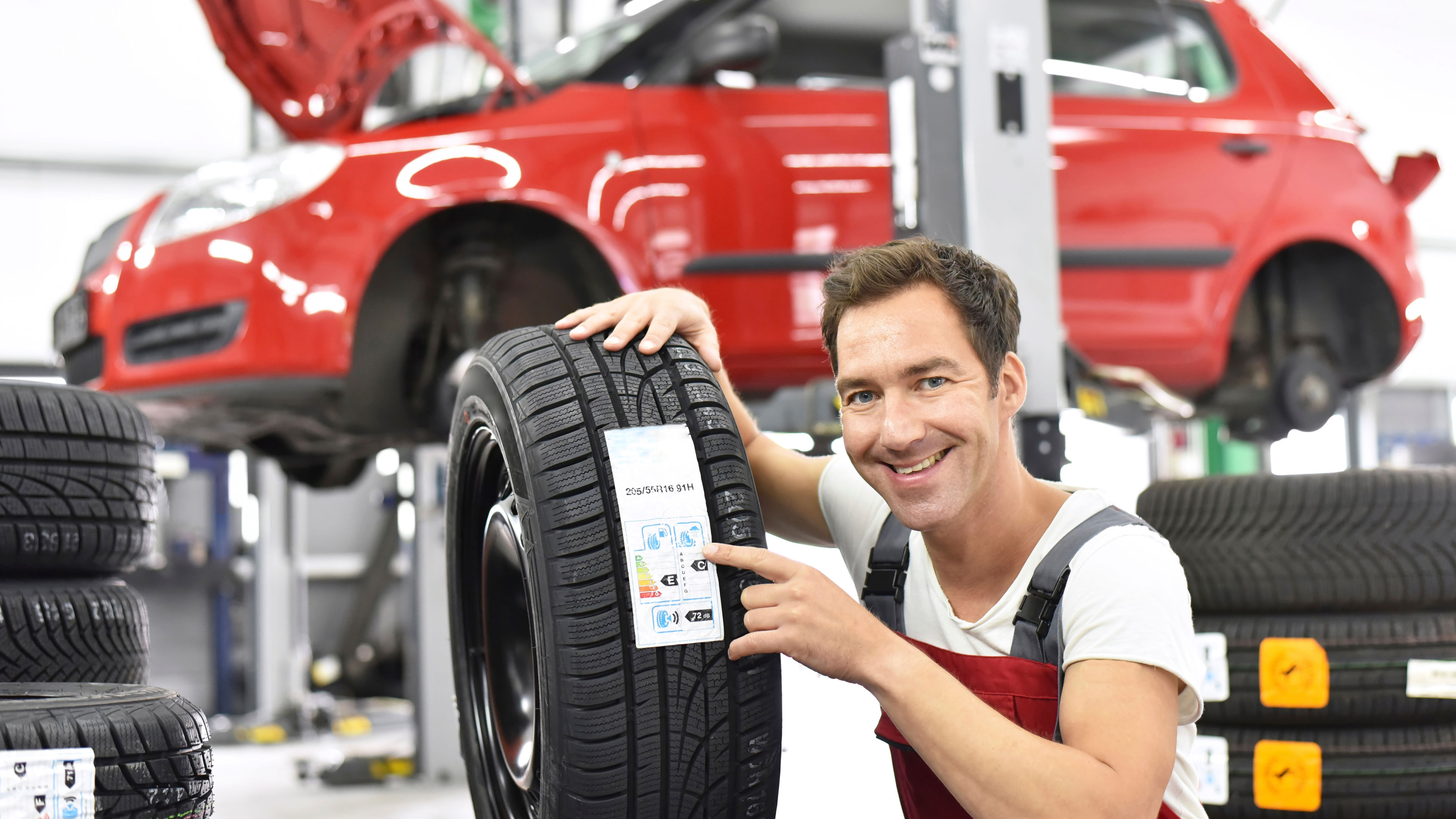 Car mechanic in a workshop changing tire, energy pass