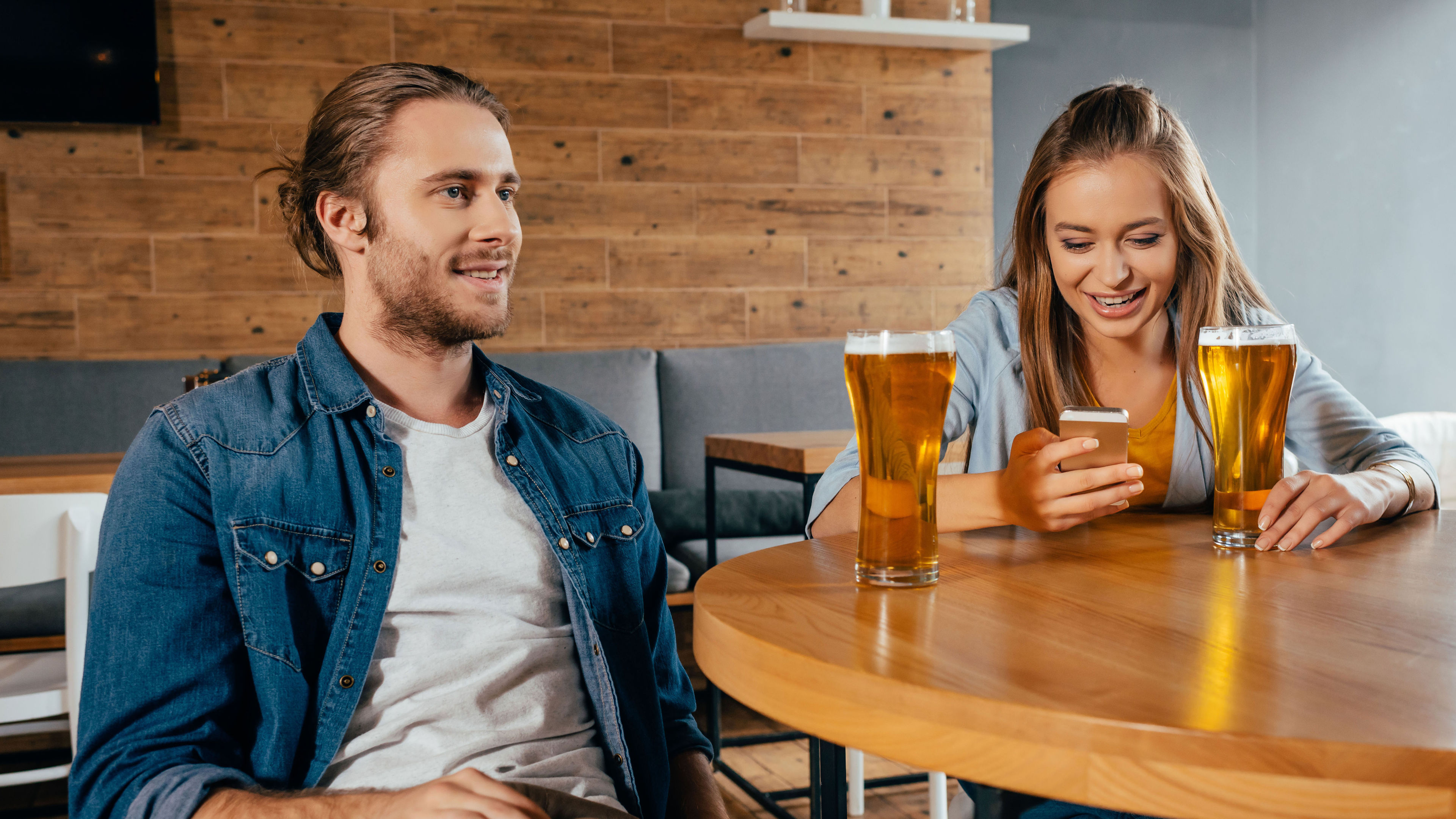 Couple sitting infront of a table with glass of beer
