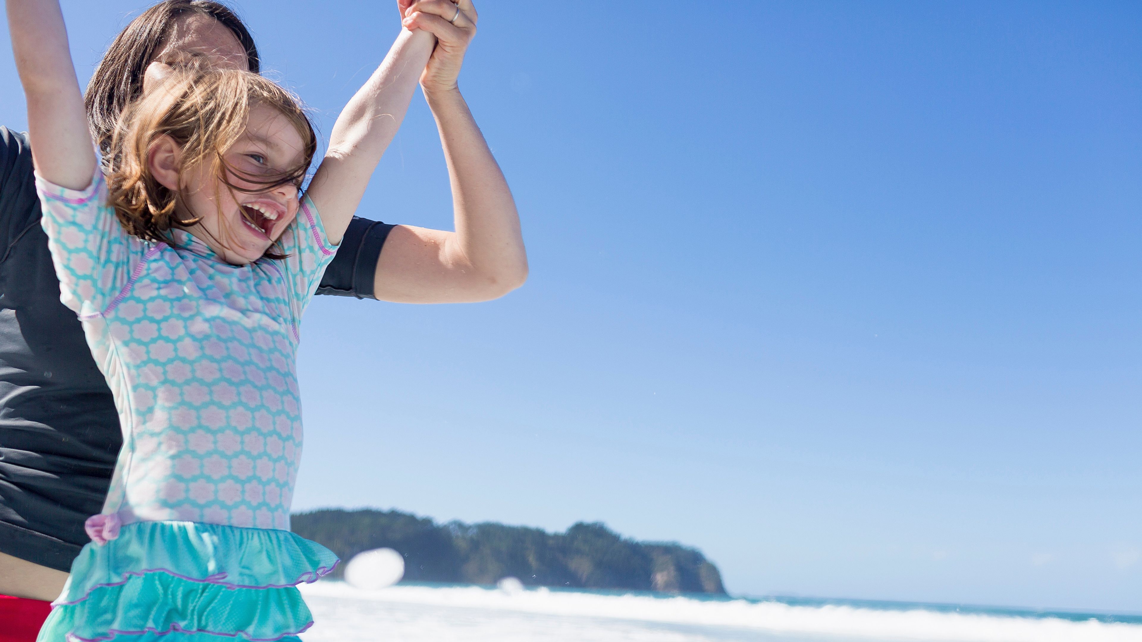 Mother And Daughter Jumping In Sea