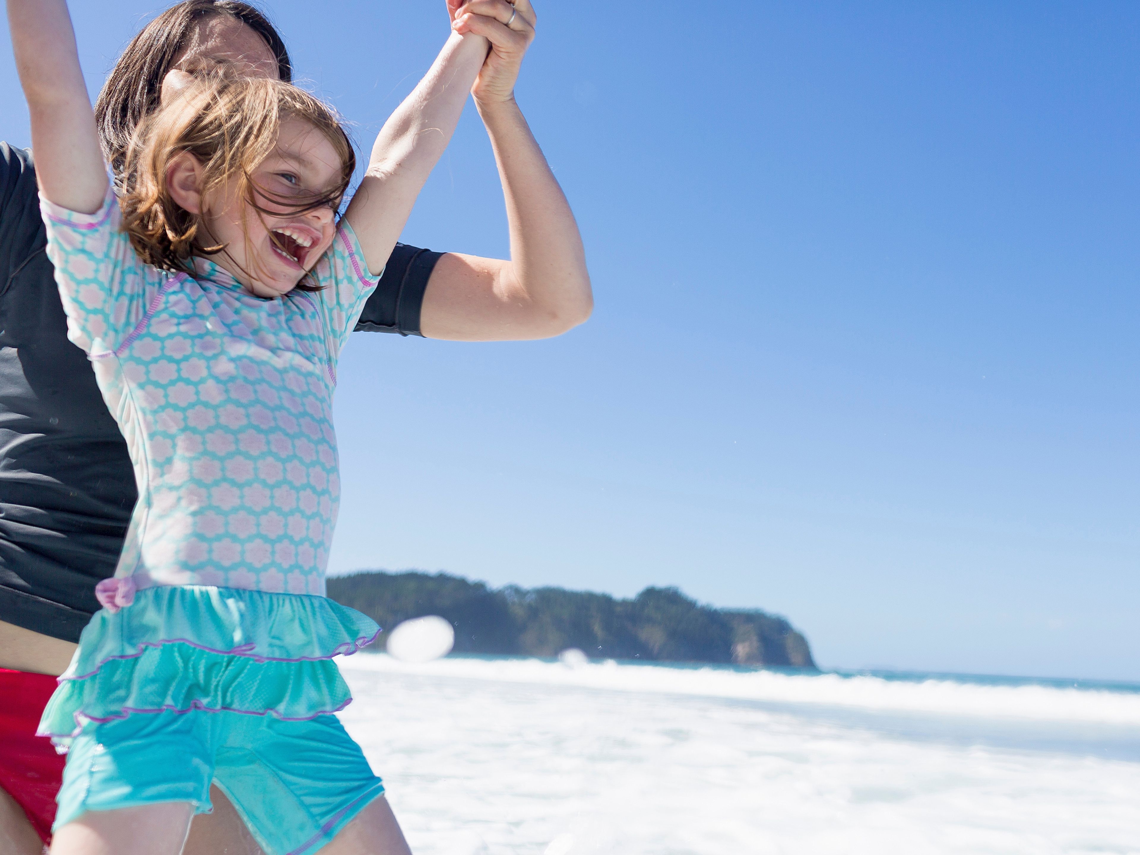 Mother And Daughter Jumping In Sea 