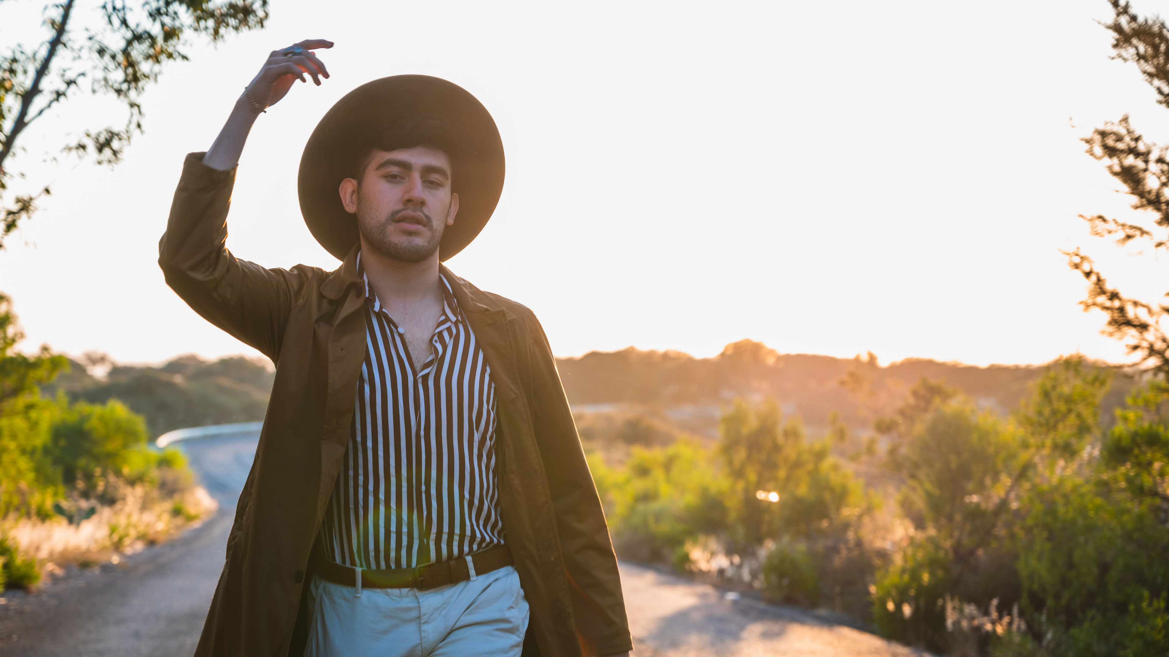 Shallow focus of a stylish confident Hispanic male walking through a road under the sunlight