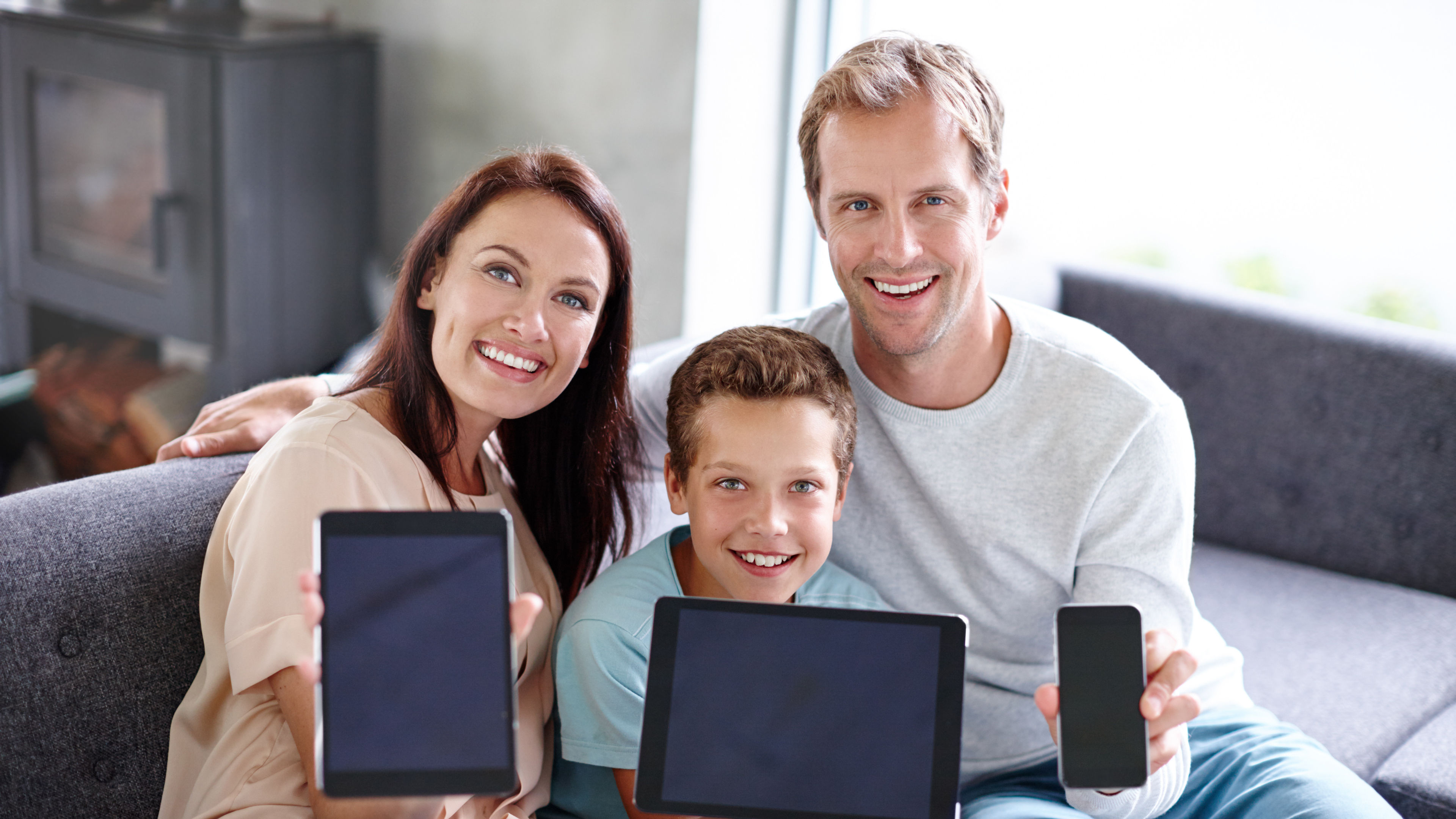Smiling Family Holding Electronic Devices