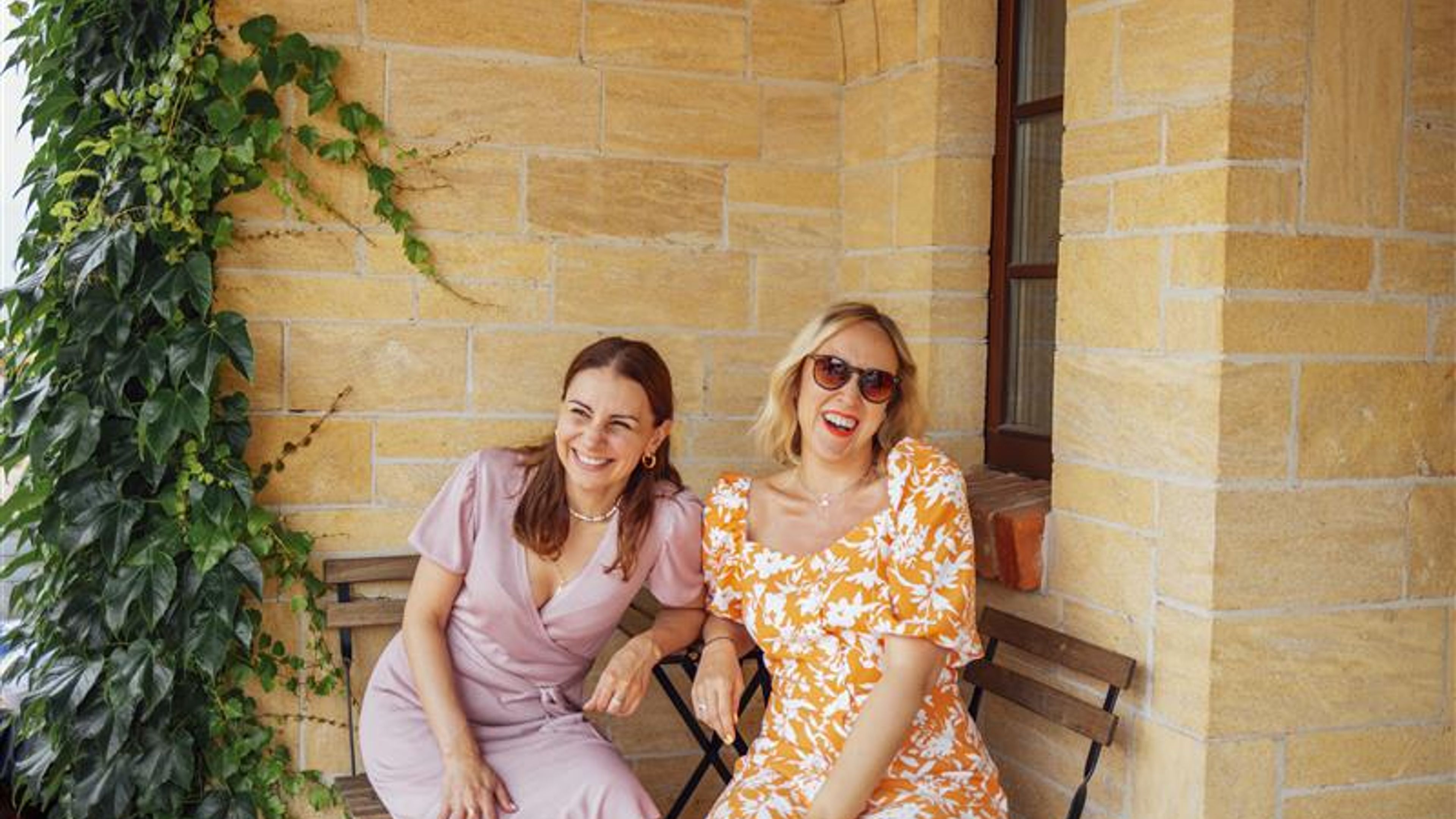 Two young women happily sitting on a couch