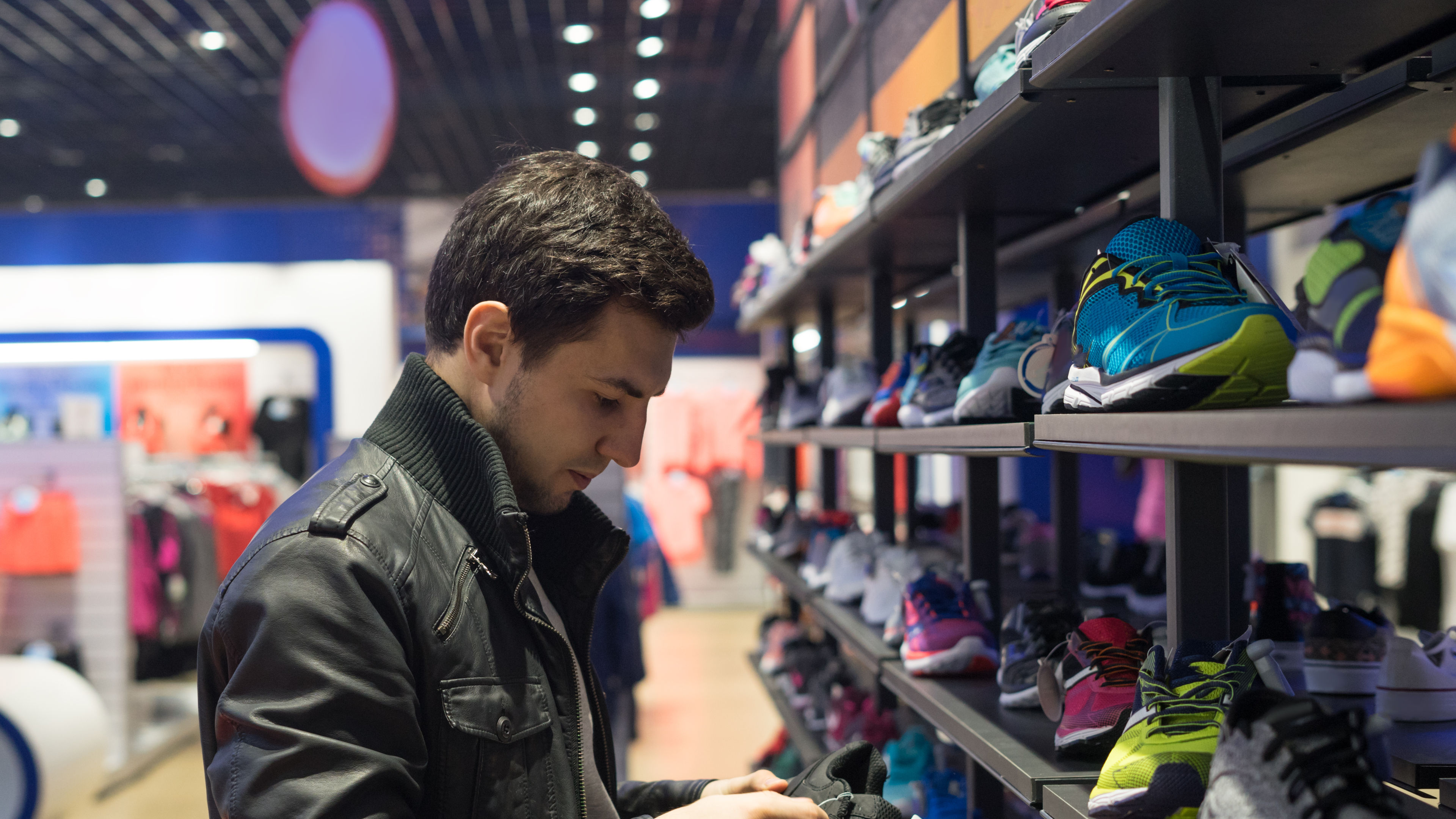 Young male customer choosing sneakers