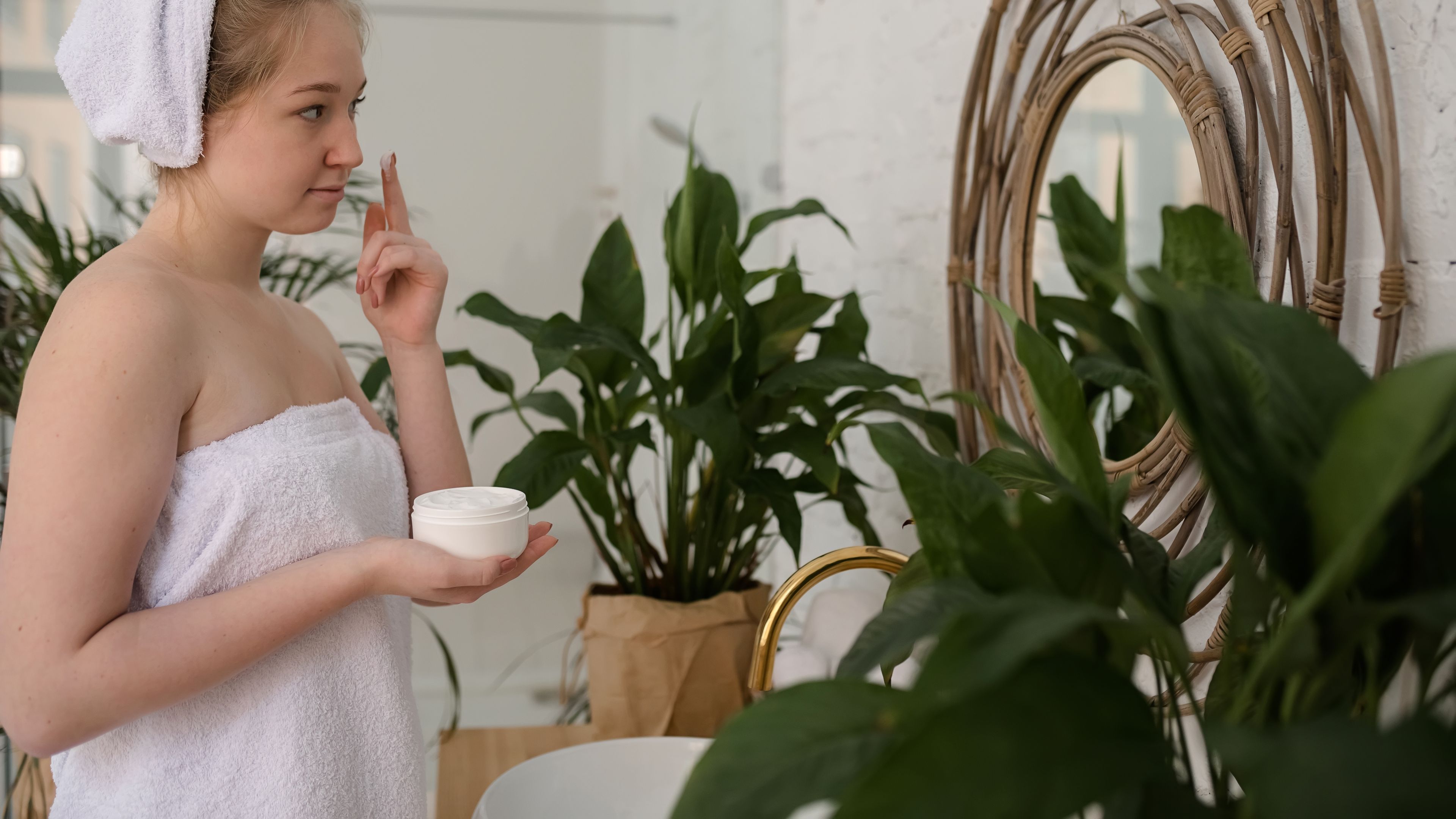 Young woman applying the cream to her face