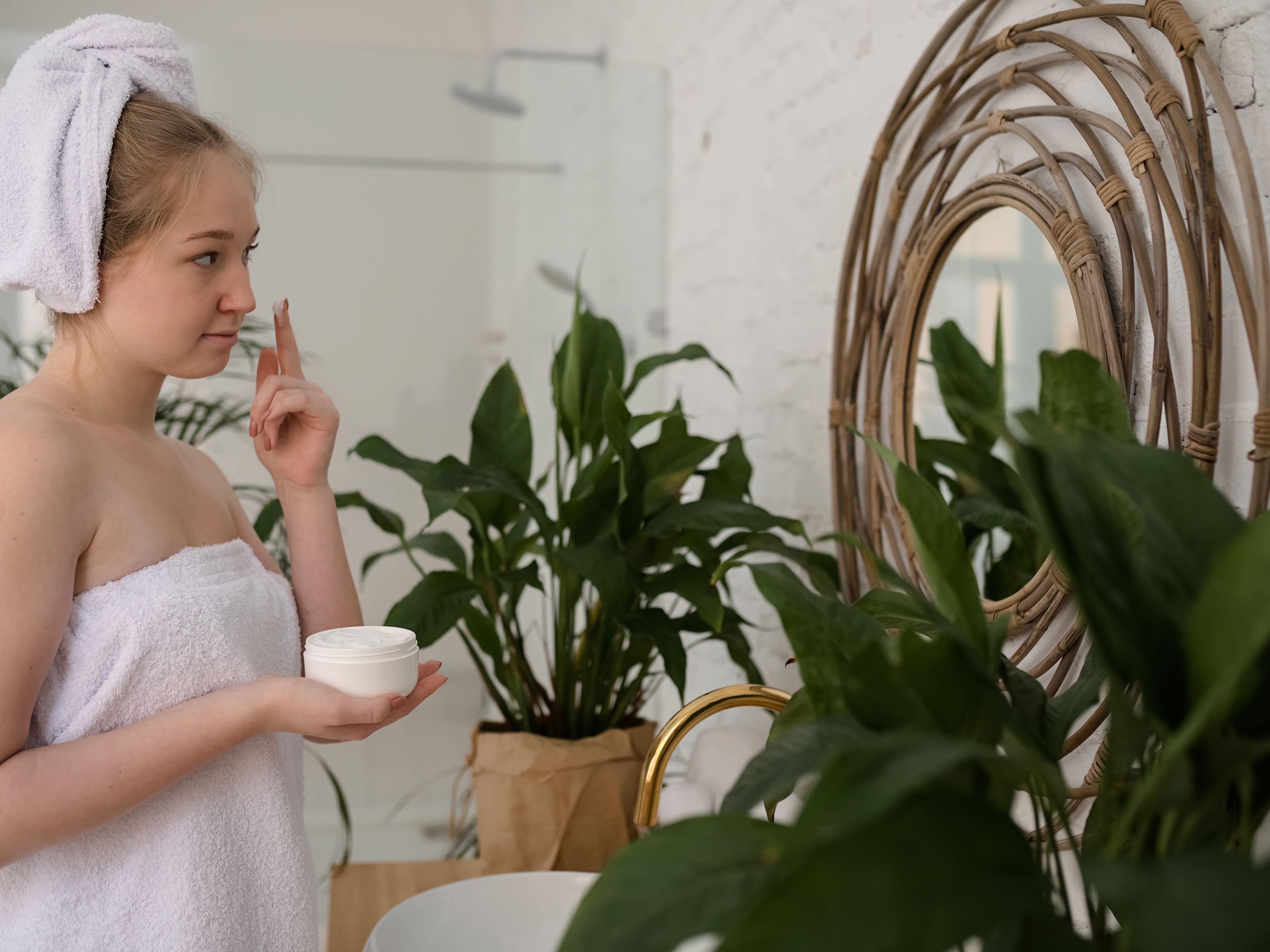 Young woman applying the cream to her face